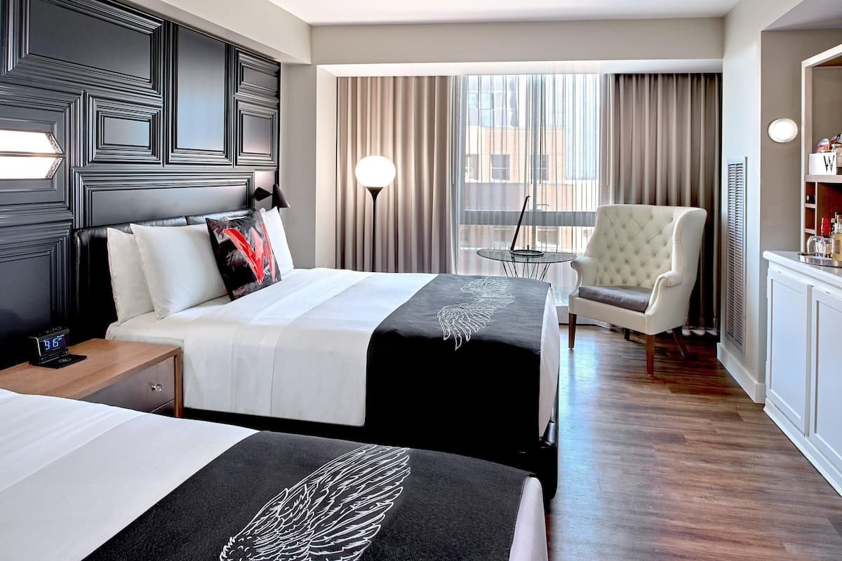 Een hotelkamer met twee bedden, een stoel, een tafeltje en een minibars.
