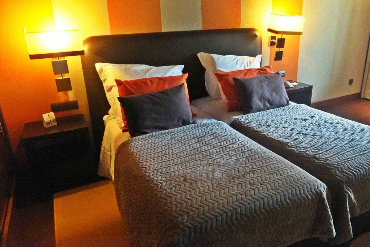 A double bed with two pillows, a nightstand, and a lamp.