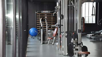 A gym with exercise equipment, a blue exercise ball, and a weight bench.