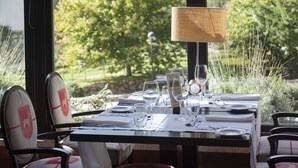 A dining table set with white tablecloths, plates, and cutlery, with a view of greenery outside. - H2otel Congress & Medical Spa (Covilhã)