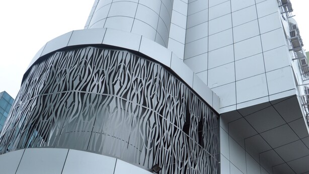 Ein modernes Gebäude mit einer geschwungenen Fassade und einem strukturierten Fensterdesign.
