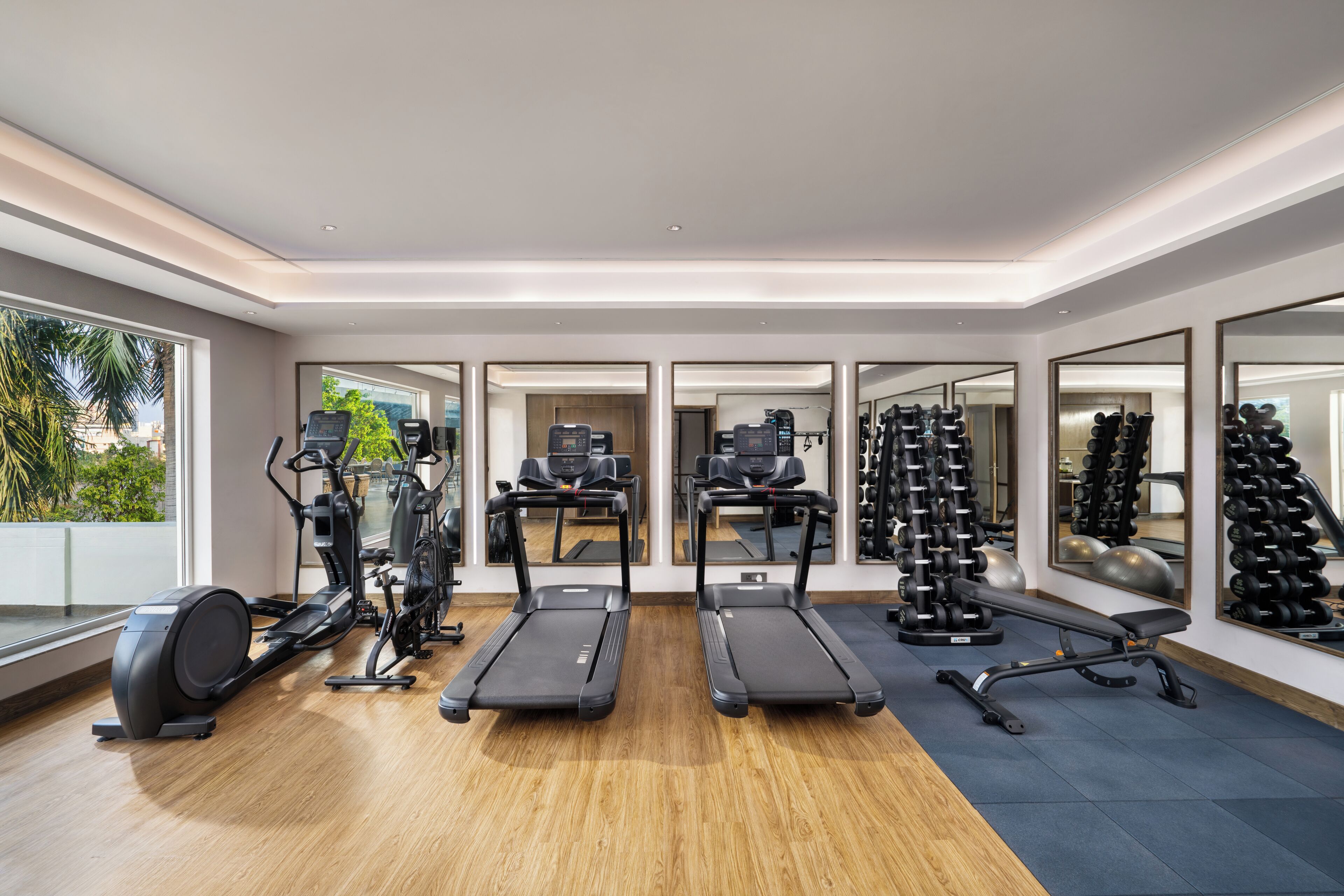 A modern gym with treadmills, an elliptical, and free weights.