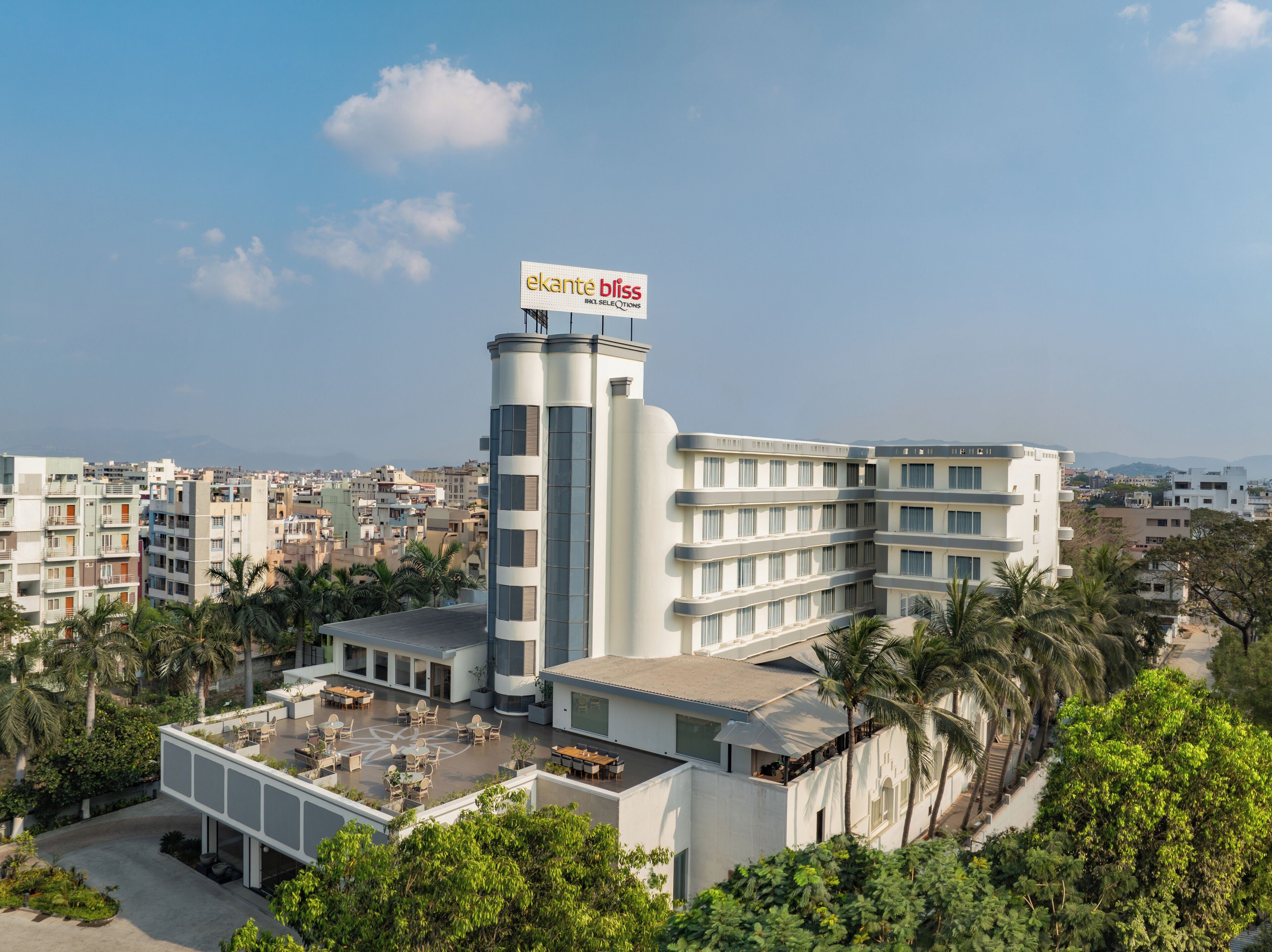 A modern hotel with a prominent sign reading "ekante bliss" and a rooftop patio area.