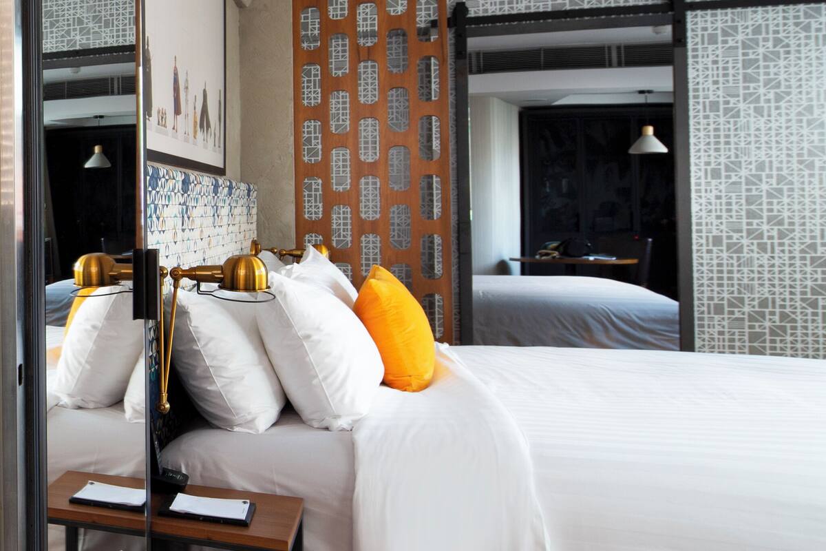 A hotel room with a large bed, a desk, and a mirror.