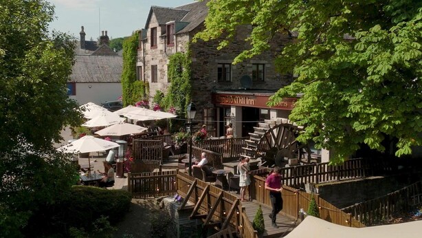 A traditional stone building with a sign reading "The Old Mill Inn."
