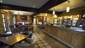 A bar area with wooden furniture, a plaid carpet, and a bar counter with various items.