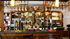 A bar area with multiple liquor bottles, a variety of glassware, and a counter with bar tools. - The Old Mill Inn (Pitlochry)