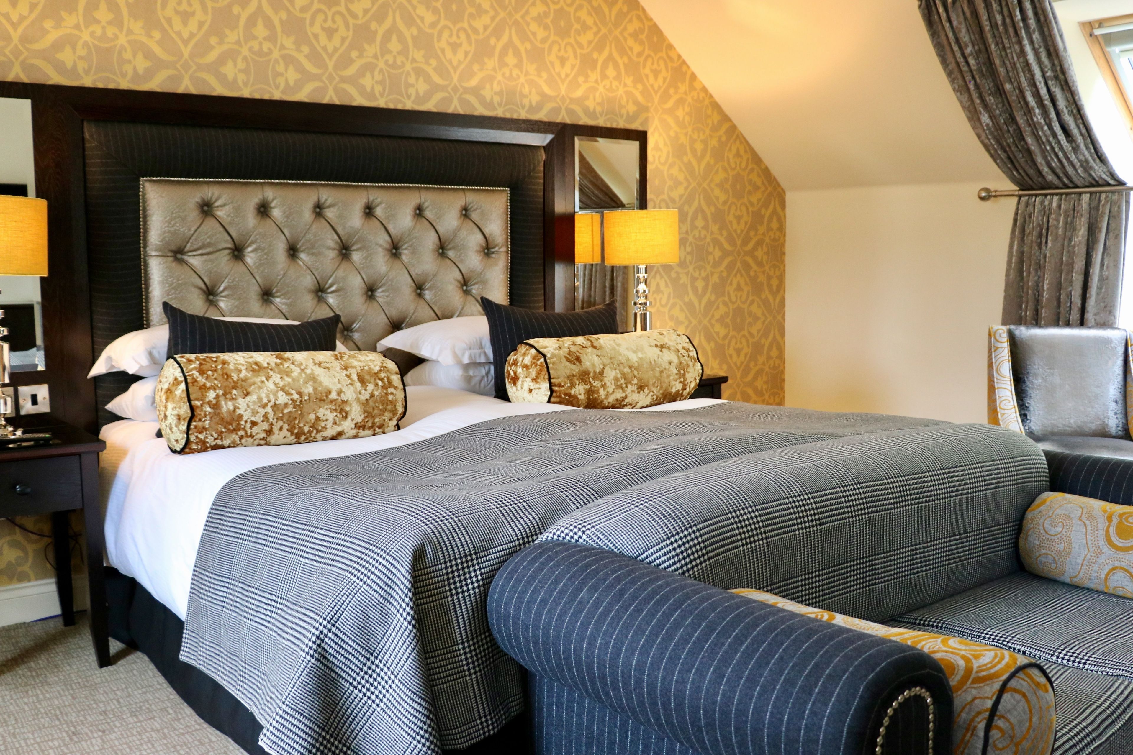 Una habitación de hotel con una cama grande, dos mesitas de noche, un sofá y un espejo.