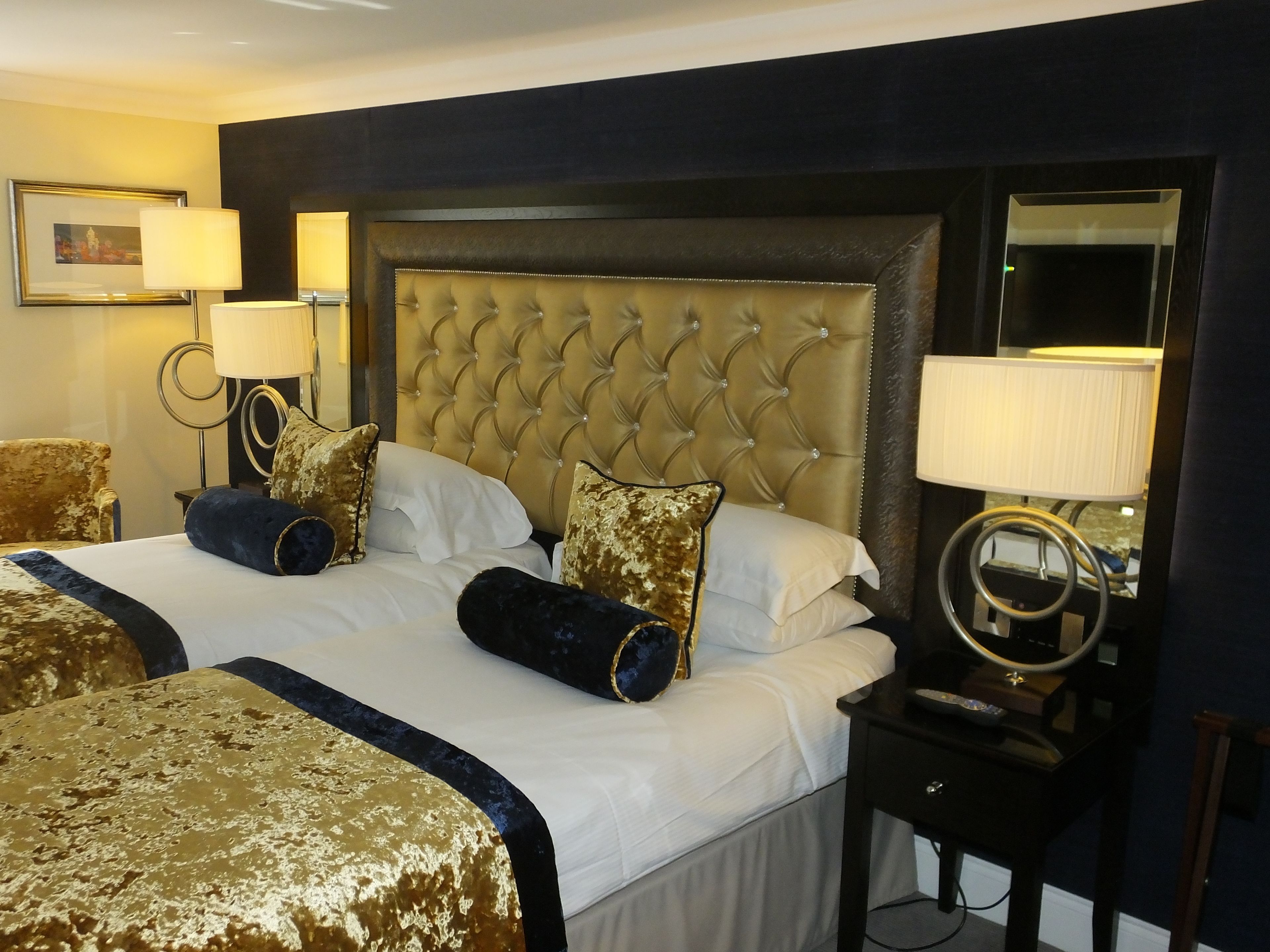 Una habitación de hotel con una cama grande, dos mesitas de noche y un espejo.