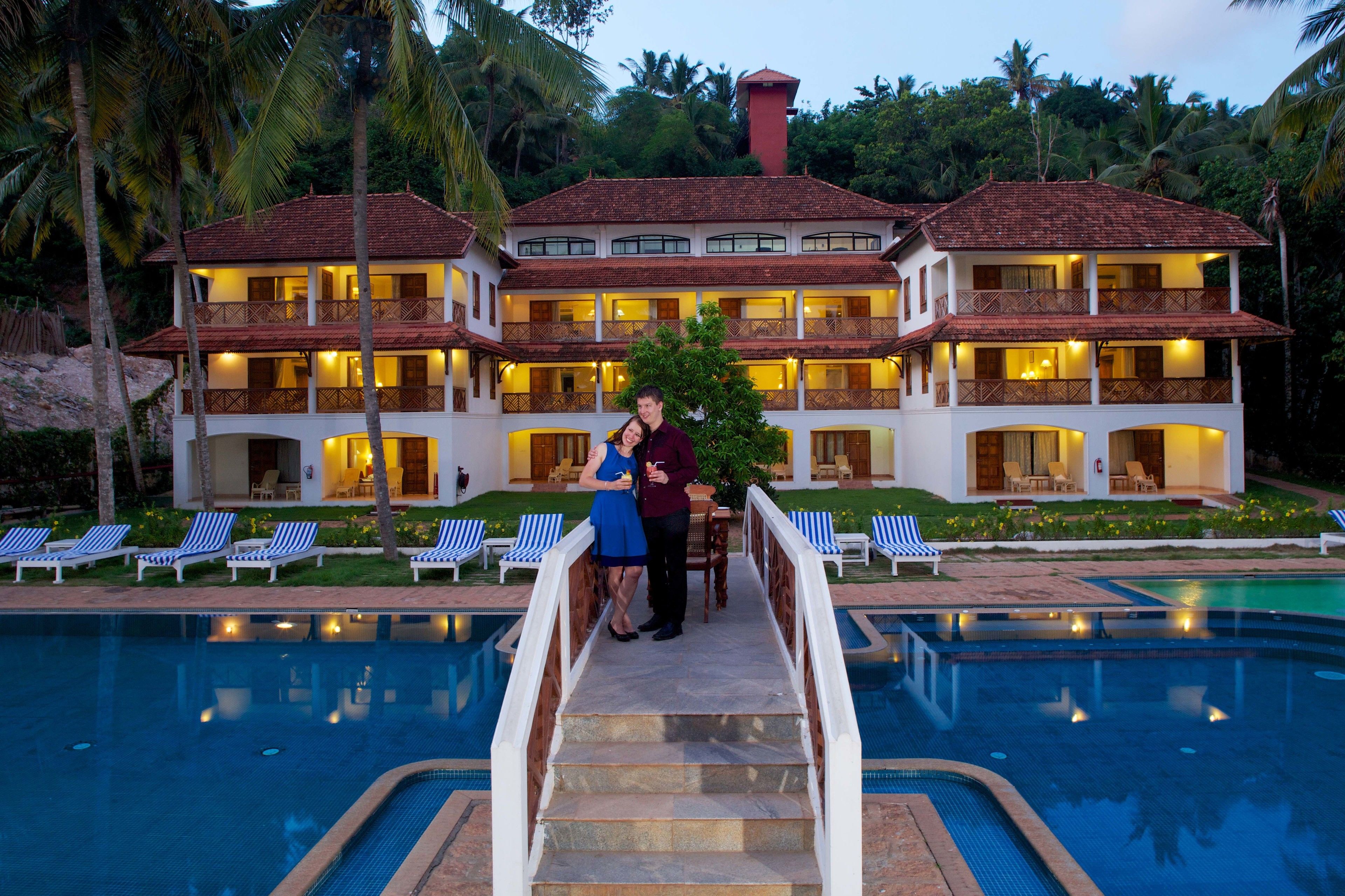 A two-story hotel with a swimming pool, multiple balconies, and a well-lit exterior.