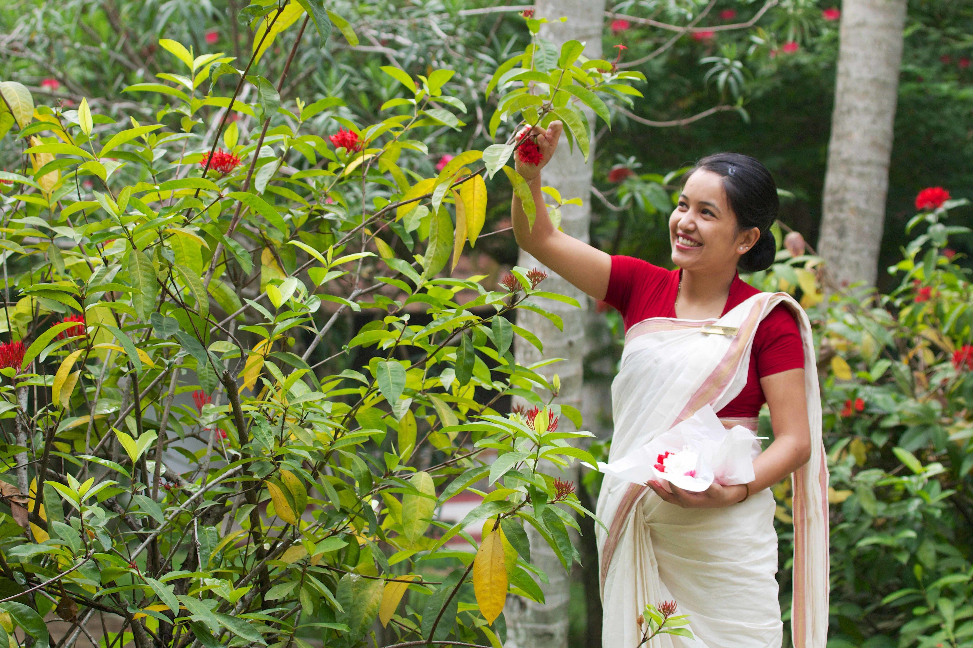 A person in traditional attire holding a flower.