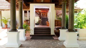 A covered entrance with wooden beams, columns, and a chandelier.