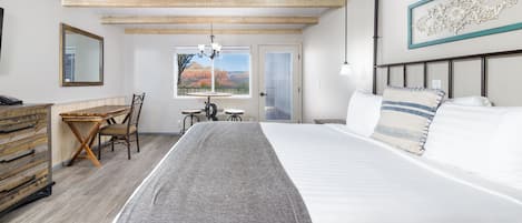 Quarto com cama, escrivaninha, cadeira, cômoda, lustre e vista para o exterior.