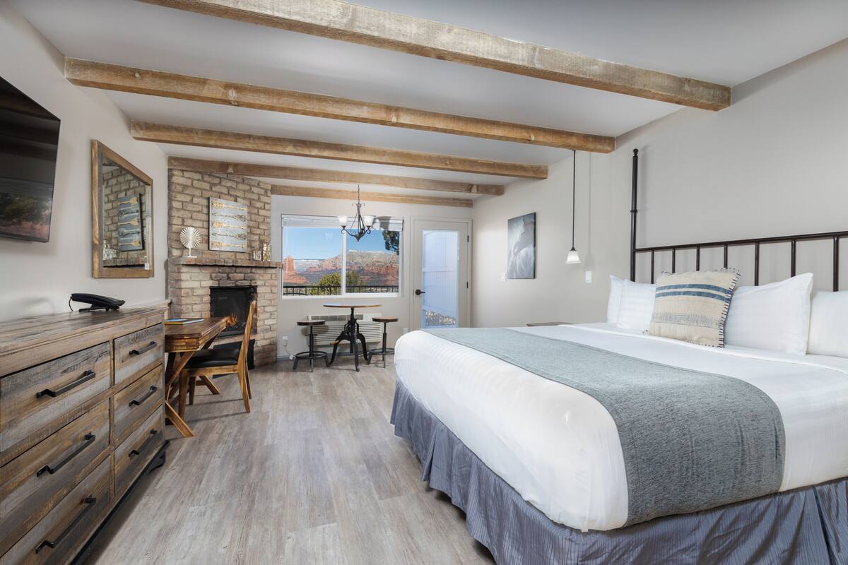 Quarto com uma cama grande, cômoda de madeira e lareira.