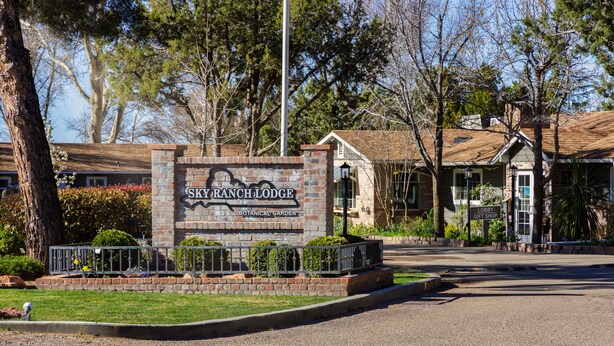 A sign for Sky Ranch Lodge with a botanical garden.