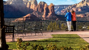 A paved outdoor area with benches and a railing, overlooking a mountainous landscape.