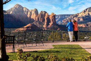 A paved outdoor area with benches and a railing, overlooking a mountainous landscape.