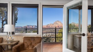 Habitació amb una finestra gran que ofereix vistes a una serralada i al skyline de la ciutat.
