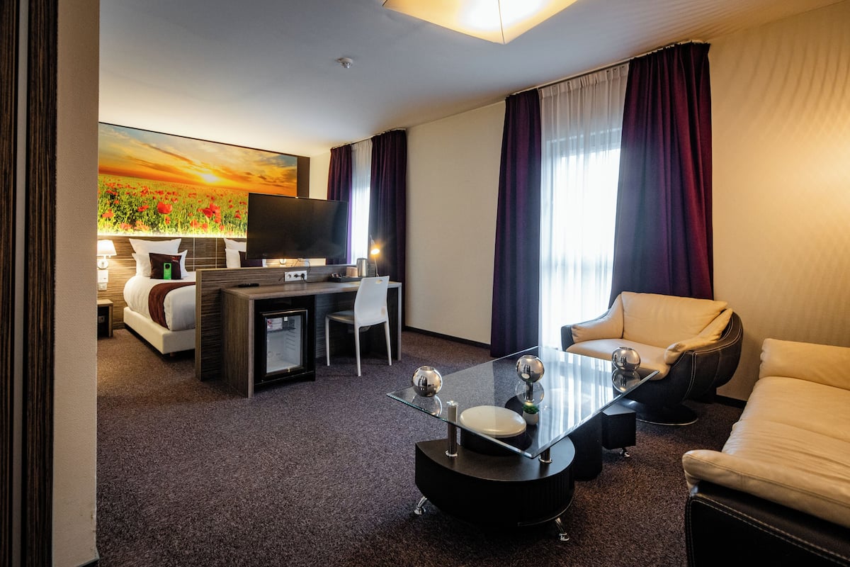 Une chambre d’hôtel comprenant un lit, un bureau avec un ordinateur, un canapé, une table basse et un téléviseur.