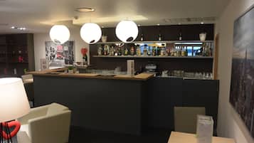 A bar area with a counter, shelves of bottles, and a seating area with chairs and a table.