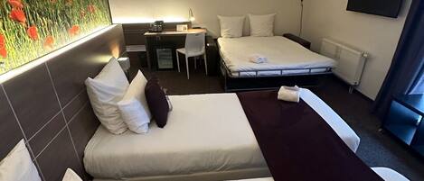 A hotel room with two beds, a desk, a chair, a TV, and a painting on the wall.