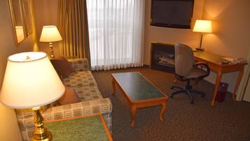 A hotel room with a sofa, two armchairs, a coffee table, a desk, and a television.