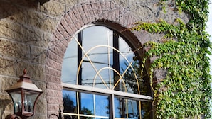 A stone building with a large arched window, a hanging lantern, and a flower box.