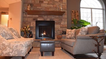 A living room with a fireplace, two sofas, and a large window.