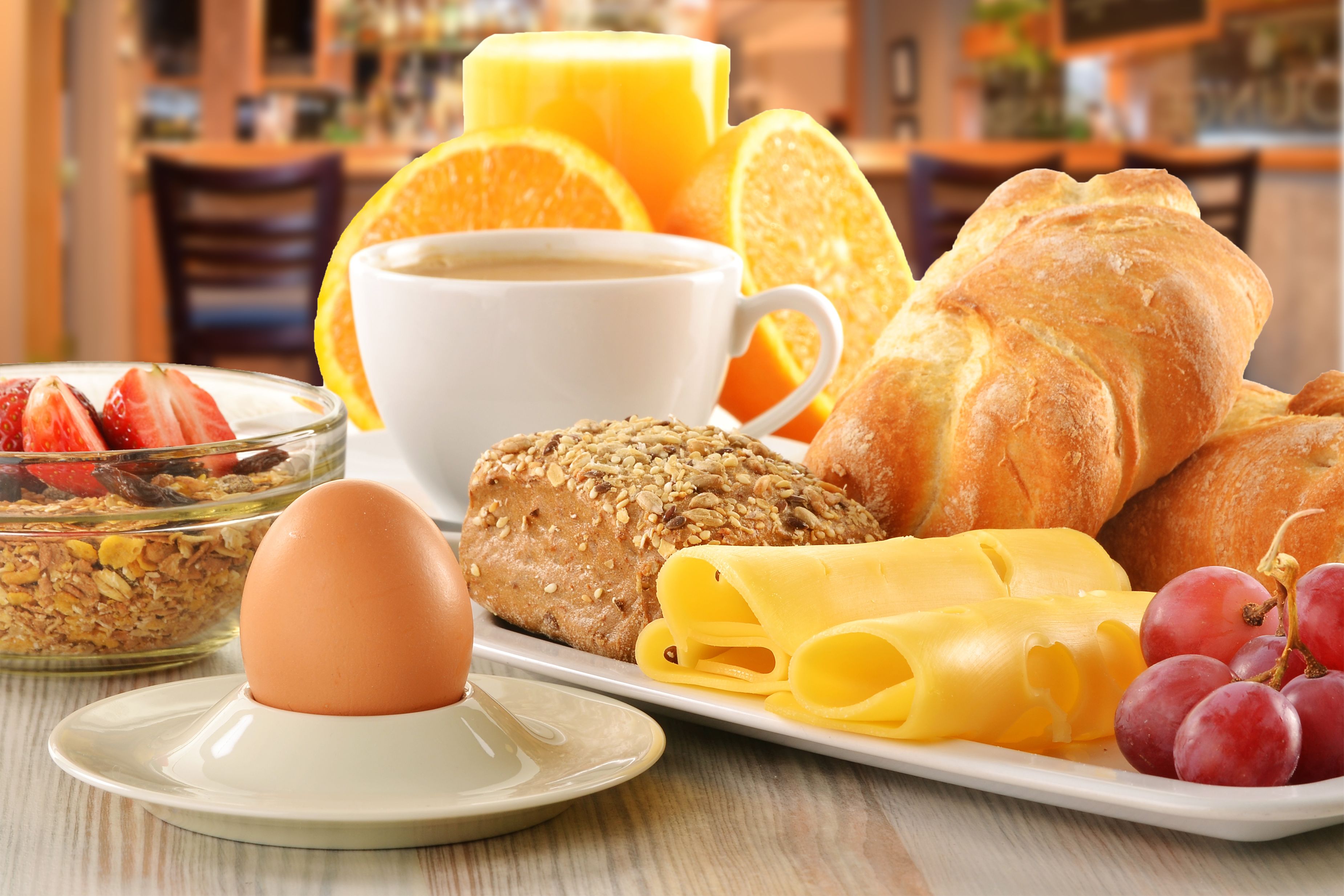 A breakfast plate with bread, cheese, grapes, a croissant, and a cup of coffee.