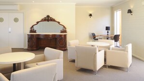 A room with a large mirror, a round table, and four white armchairs. - Drouin Motel (Drouin)