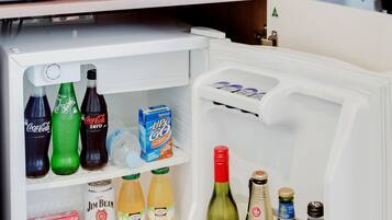 Un petit réfrigérateur rempli de boissons et d’en-cas, un four à micro-ondes et une petite étagère avec des produits pour le petit-déjeuner.