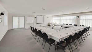 A conference room with a long table, chairs, a projector screen, and a whiteboard. - Drouin Motel (Drouin)