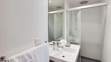 Casa de banho moderna com cabine de duche em vidro, lavatório branco e porta-toalhas.