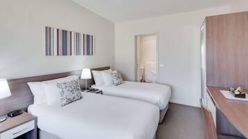 A hotel room with two beds, a desk, and a bathroom door.