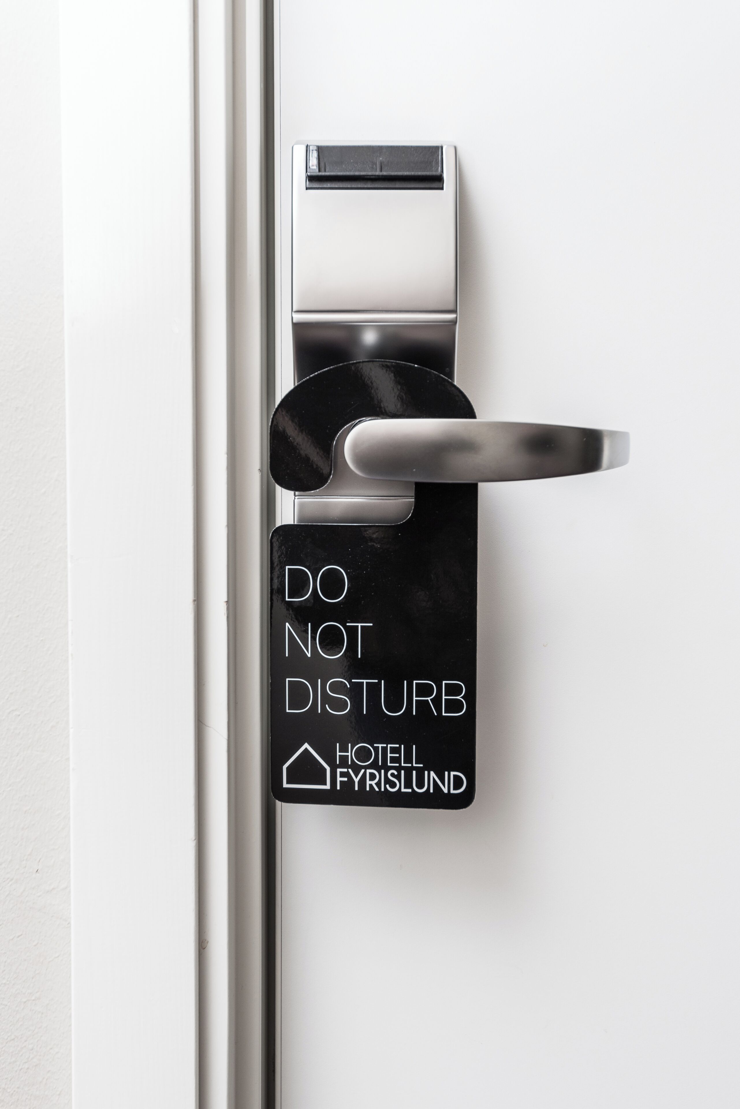 A hotel door with a "DO NOT DISTURB" sign and a keycard slot.