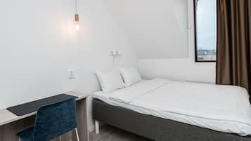 A modern, minimalist bedroom with a single bed, a desk, and a chair.