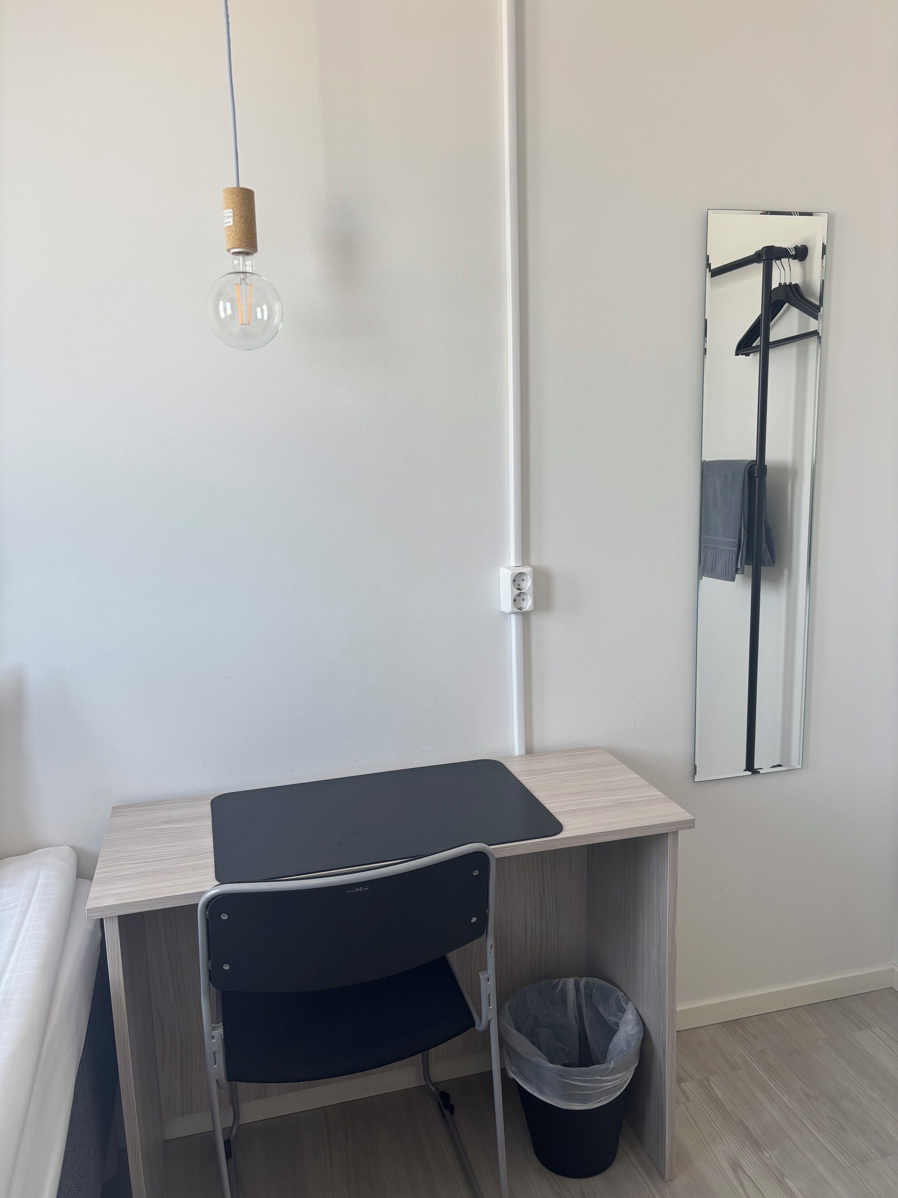 A compact workspace with a desk, chair, and a hanging light fixture.