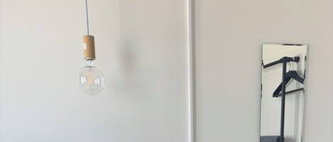 A compact workspace with a desk, chair, and a hanging light fixture.