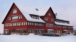 A red building with multiple windows and a snow-covered roof. - Hotell Fyrislund (Uppsala)