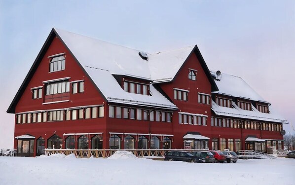 A red building with multiple windows and a snow-covered roof. - Hotell Fyrislund (Uppsala)
