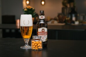 A glass of beer, a bottle of beer, and a jar of snacks on a table. - Hotell Fyrislund (Uppsala)