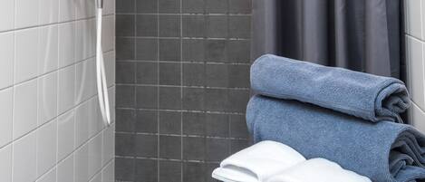 A bathroom with a shower, a towel rack, and a stool.