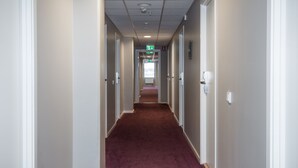 A long, narrow hotel corridor with carpeted floors and white walls. - Hotell Fyrislund (Uppsala)