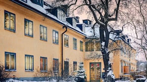 Un edificio amarillo con varias ventanas y una entrada cubierta de nieve.