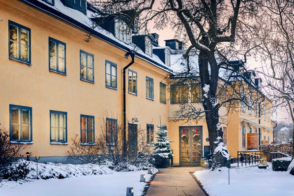 A yellow building with multiple windows and a snow-covered entrance.