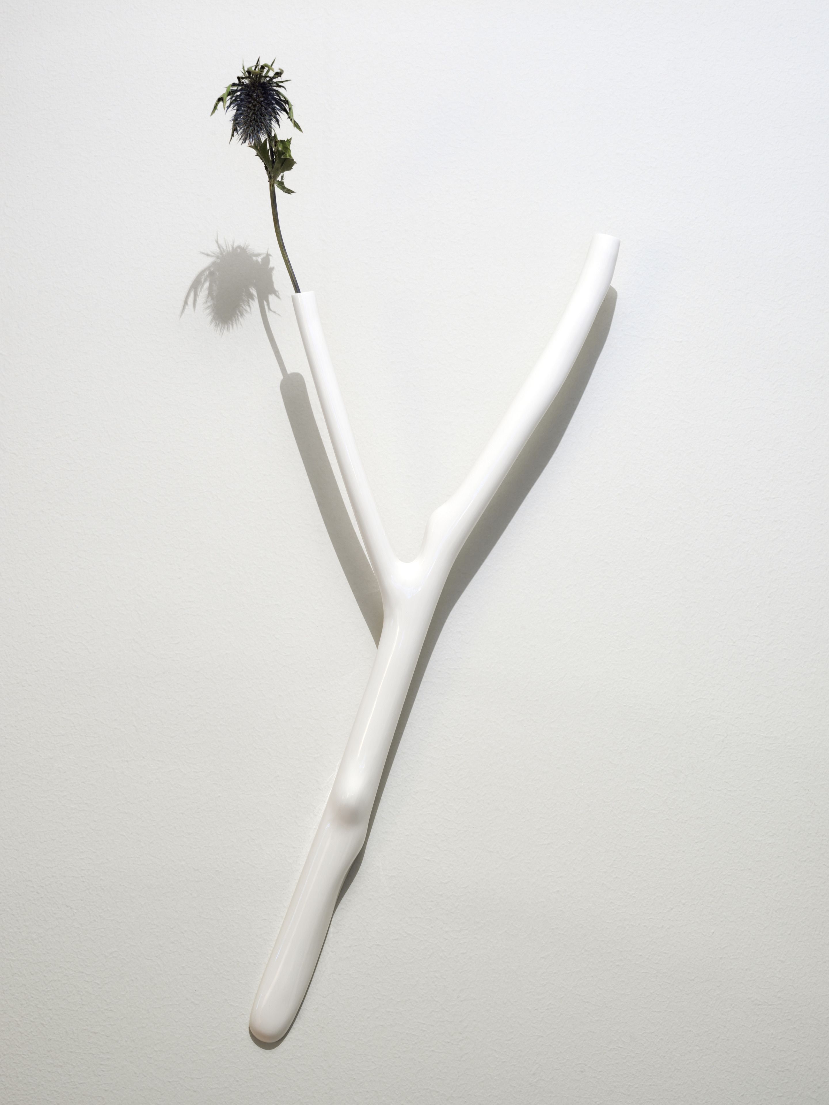Ett vitt, Y-format föremål med en enda blomma på toppen.
