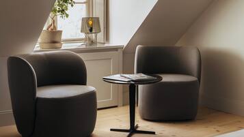 En modern loftlägenhet med två stoppade fåtöljer, ett litet runt bord och en lampa.