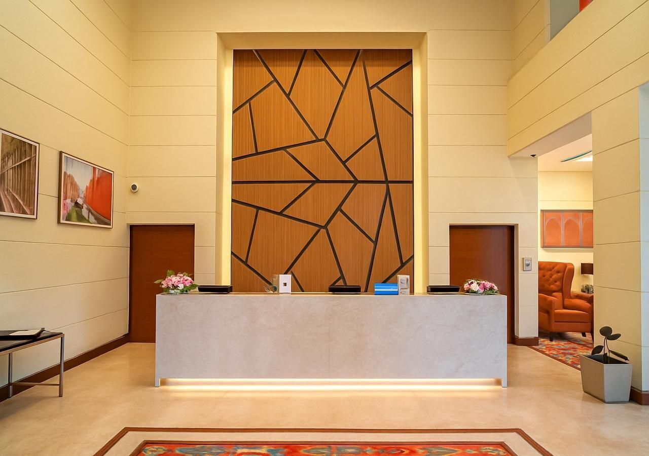 A reception desk with a geometric wooden panel, a modern chair, and a framed artwork on the wall.