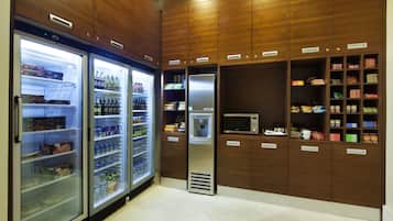 Una kitchenette con dos refrigeradores, un microondas y varios armarios para almacenamiento de alimentos.