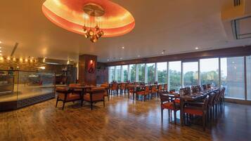 A spacious dining area with a large, circular ceiling light fixture and a view of the outdoors through large windows.